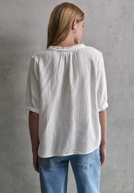 Frau mit weißen Shirt und Jeans steht mit dem Rücken zur Kamera.